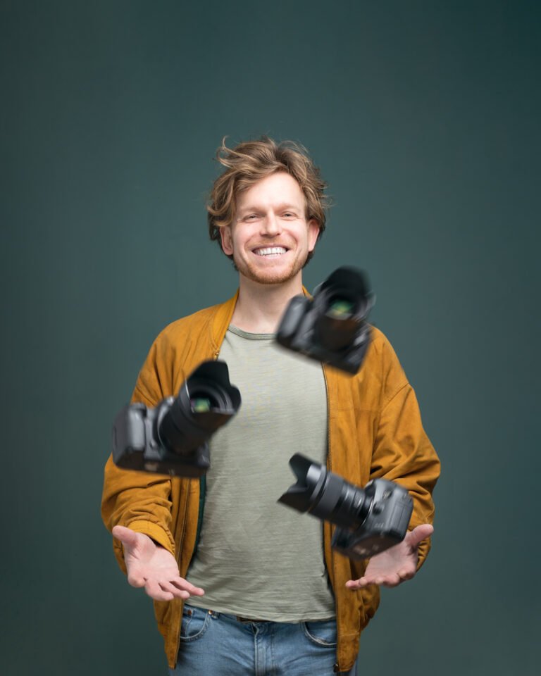 Ein Fotograf, der mit drei Kameras auf einem Studioporträt jongliert