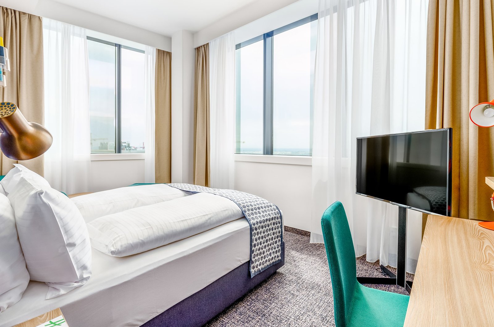 Ein einfaches Hotelzimmer mit Möbeln und Blick von einem hohen Wolkenkratzer in Wien
