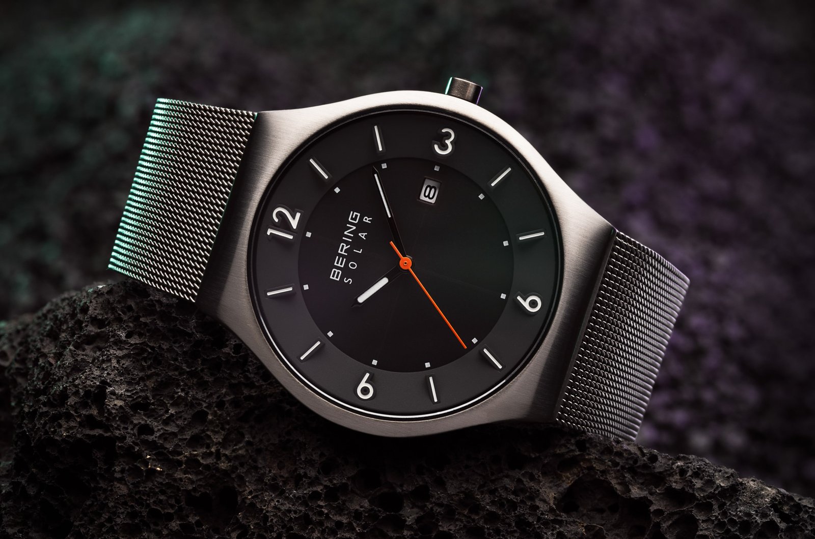 Ein detailliertes Bild einer Herrenuhr mit Metallarmband, die auf einem Vulkanstein liegt
