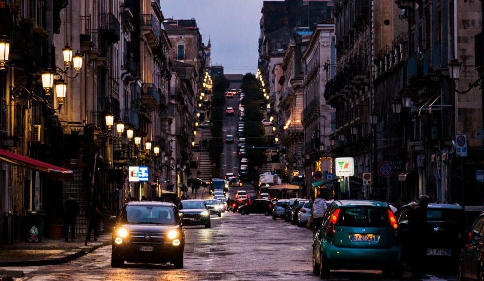 Night scene of Catania from a long street with a hill in the distance
