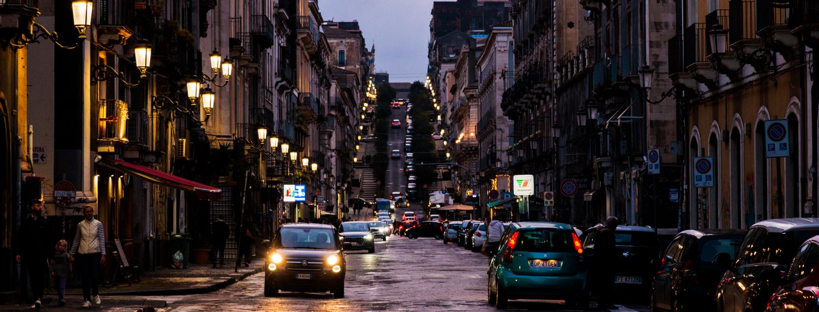 Night scene of Catania from a long street with a hill in the distance